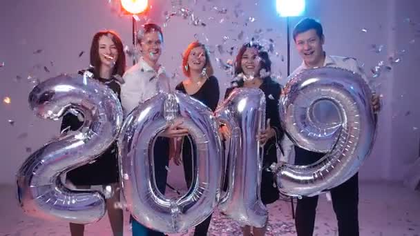 Nuovo concetto anno 2019. Gruppo di giovani allegri in possesso di palloncini numerici, ricoperti di coriandoli — Video Stock
