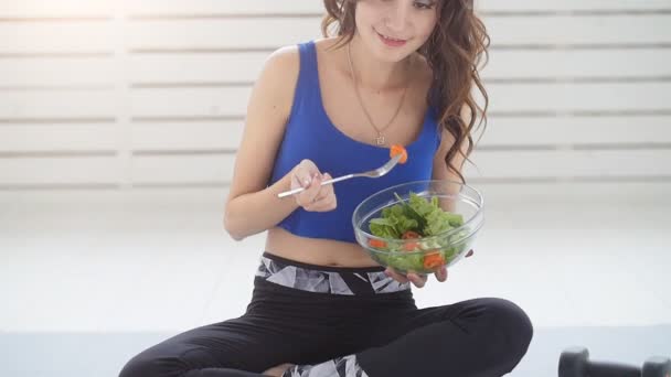 Healthy lifestyle concept. Smiling sporty young woman with green salad at home — Stock Video