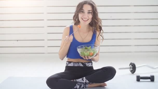 健康的なライフ スタイルのコンセプト。自宅のグリーン サラダと笑顔のスポーティな若い女性 — ストック動画