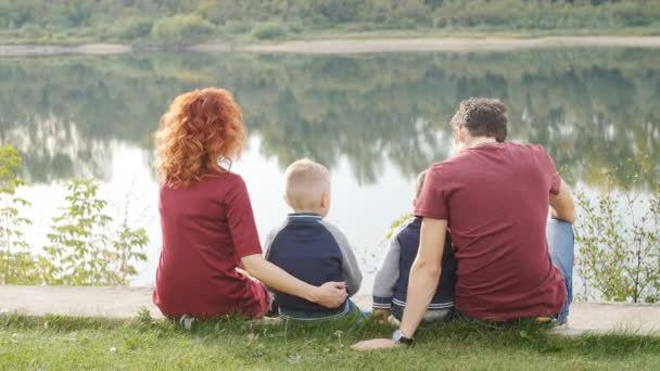 Aile ve çocuk kavramı. Nehir kenarında yürüyüş iki oğlu ile genç çift — Stok video