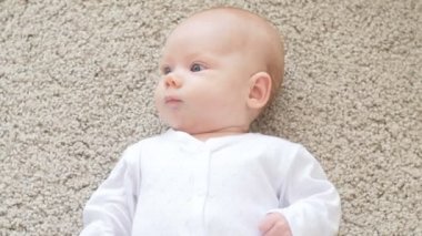 Mutlu bebek yalan halı zemin, bebek çocuk gülümseyen kız beyaz giyim üzerine