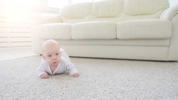 快乐的婴孩躺在地毯背景, 微笑的婴儿女孩在白色服装 — 图库视频影像