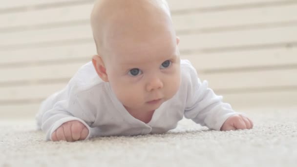 Happy Baby liggande på matta bakgrunden, leende spädbarn Kid flicka i vita kläder — Stockvideo