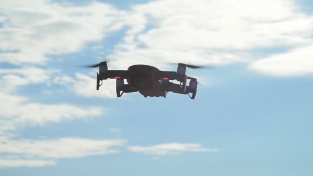Concepto de drones personales y fotografía aérea. Quadcopter volando sobre la cabeza en cielo azul nublado — Vídeo de stock