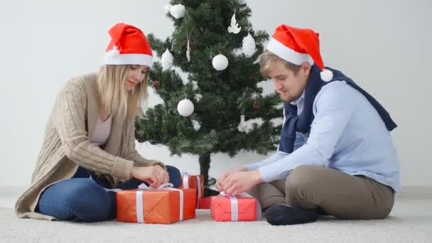Концепція Різдва і щасливого Нового року. Щаслива молода пара відкриває різдвяні подарунки — стокове відео