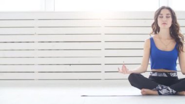 Spor yapan genç bir kadın yoga yapıyor, Yarım Lotus egzersizi yapıyor, Siddhasana pozu veriyor, iç mekan, iç mekan.