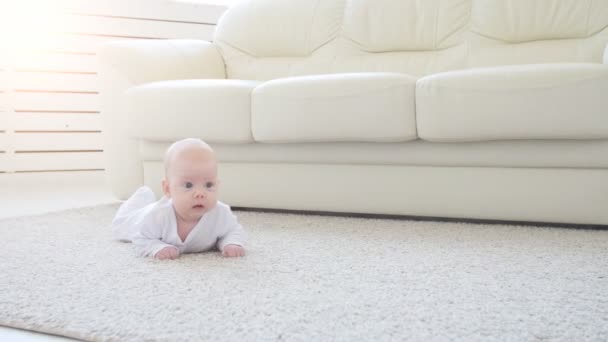 Concepto de hijos y paternidad. Lindo bebé feliz está acostado en la alfombra — Vídeo de stock