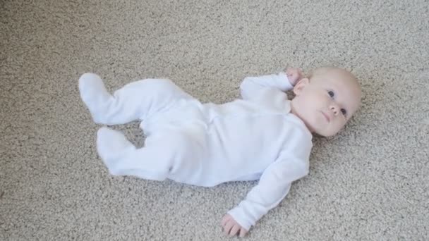 Concepto de hijos y paternidad. Lindo bebé feliz está acostado en la alfombra — Vídeo de stock