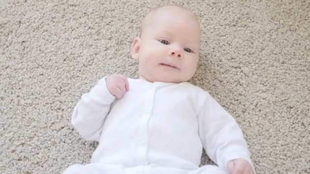 Concepto de hijos y paternidad. Lindo bebé feliz está acostado en la alfombra — Vídeos de Stock