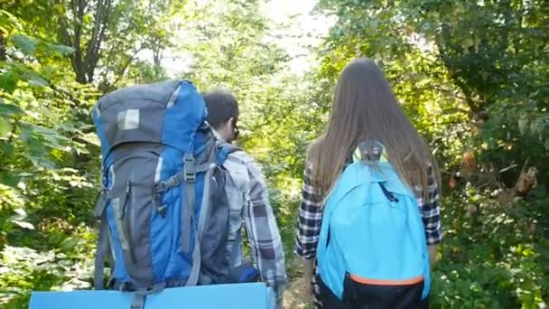 숲에서 배낭과 젊은 커플. 여행 및 하이킹 개념 — 비디오