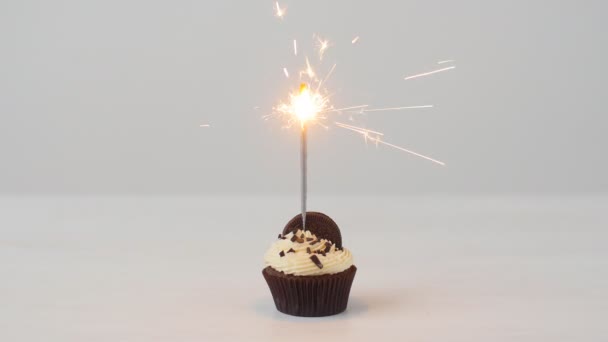 Delicioso cupcake de cumpleaños con bengala ardiente en la mesa blanca — Vídeo de stock