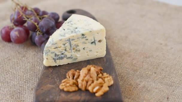 Μπλε τυρί και καρύδια περιστρέφονται σε ένα ταμπλό με ξύλινα ΜΕΡΙΔΑ — Αρχείο Βίντεο