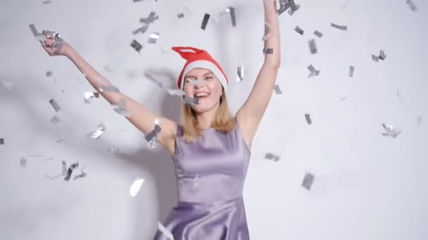 Joyeux jeune femme dans le chapeau de Père Noël à la fête avec confettis tomber — Video