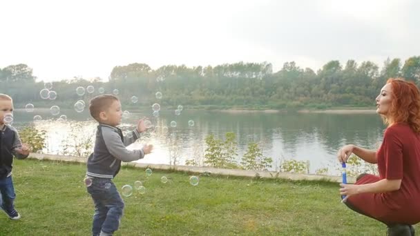 Concepto de familia e hijos. Pareja joven con dos hijos caminando junto al río — Vídeos de Stock