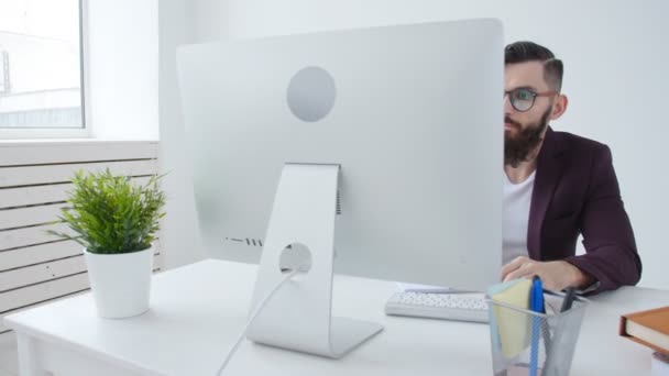 Concepto de freelancing y oficina de trabajo. Joven empleado elegante mirando el monitor de la computadora durante el día de trabajo en la oficina — Vídeo de stock