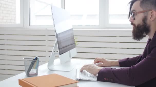 Concepto de freelancing y oficina de trabajo. Joven empleado elegante mirando el monitor de la computadora durante el día de trabajo en la oficina — Vídeos de Stock