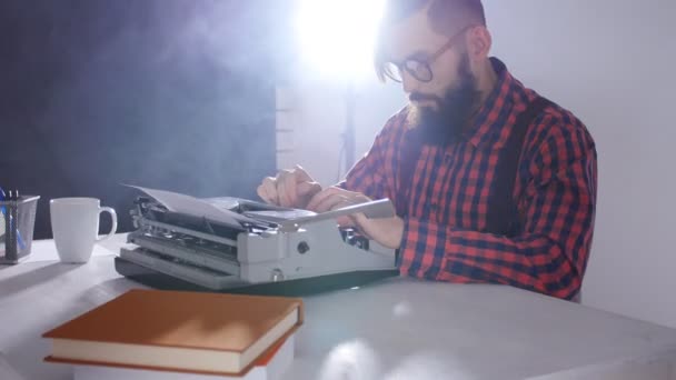 Концепция ретро писателя. Стильный молодой человек с бородой пишет на старой пишущей машинке — стоковое видео