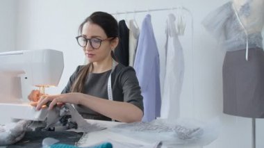 Küçük iş ve hobi kavramı. Onun Studio bir dikiş makinesi üzerinde çalışan genç kadın tasarımcı kıyafet
