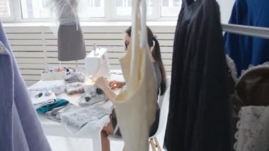 Küçük iş ve hobi kavramı. Onun Studio bir dikiş makinesi üzerinde çalışan genç kadın tasarımcı kıyafet