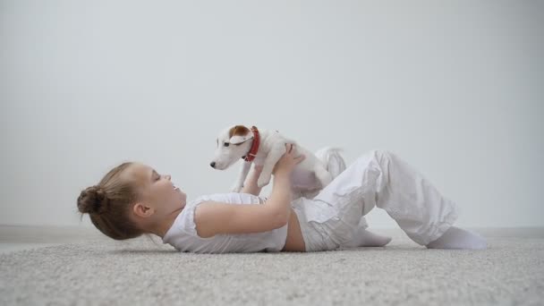 Concepto de mascotas y perros. Linda niña jugando con un cachorro en casa — Vídeos de Stock