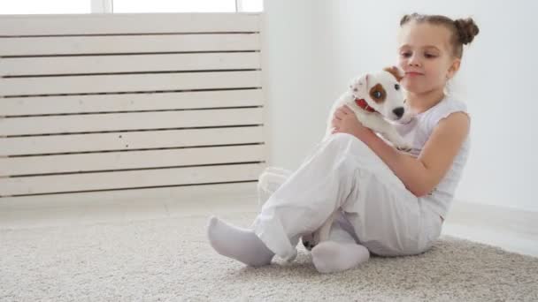 Sällskapsdjur och hund koncept. Söt liten flicka som leker med en valp hemma — Stockvideo