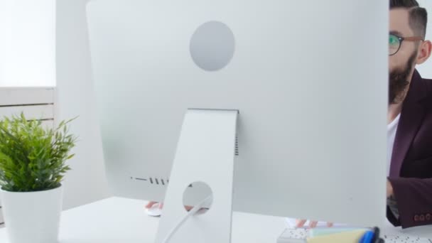 Ofis işleri veya freelancing kavramı. Şık adam ofiste bilgisayarda çalışan genç sakallı — Stok video