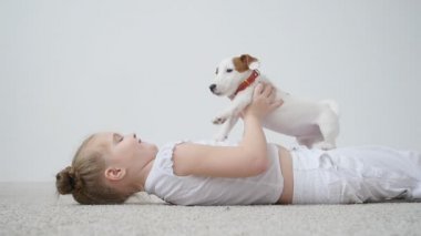 Evde beslenen hayvan kavramı. Sevimli kız beyaz iç bir köpek vasıl ev ile oynarken