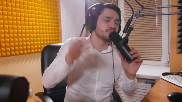 Concepto de radio y transmisión en vivo. Hombre joven con auriculares hablando por micrófono, radio en línea . — Vídeos de Stock