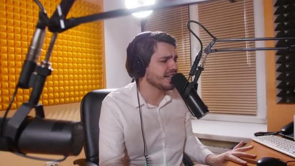 Rádio a živé vysílání konceptu. Mladý muž se sluchátky mluvit na mikrofon, online rádia. — Stock video
