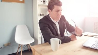 Güneşli ofiste onun masasında oturan genç adam