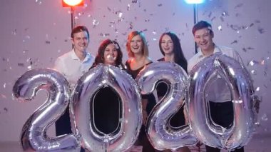 Yeni yıl 2020 kavramı. Gençlerin grup numarası balon, konfeti ile duş holding neşeli