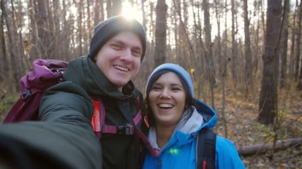 Caminhadas e conceito de mochila. Jovem casal feliz com mochilas na floresta e fazer selfie — Vídeo de Stock