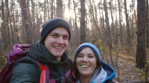 Concepto de senderismo y mochilero. Joven pareja feliz con mochilas en el bosque y haciendo selfie — Vídeos de Stock