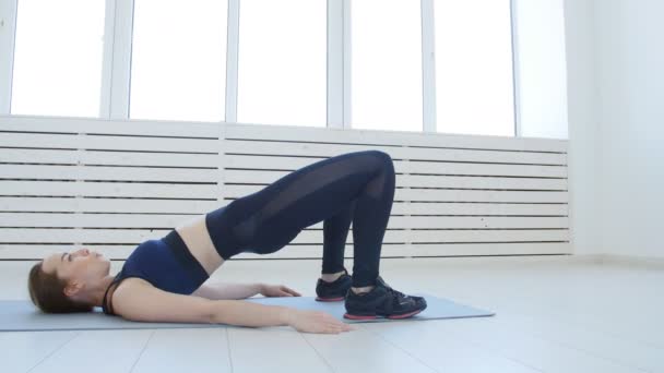 Konzept von Sport und Heimfitness. junge Frau macht Fitnessübungen in einem weißen Innenraum — Stockvideo