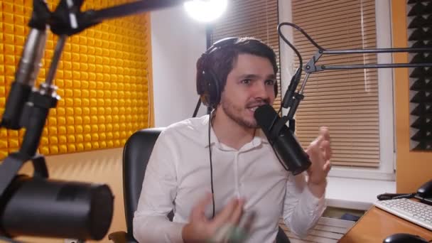 Un giovanotto con le cuffie che parla al microfono. Concetto di radio e podcasting online . — Video Stock