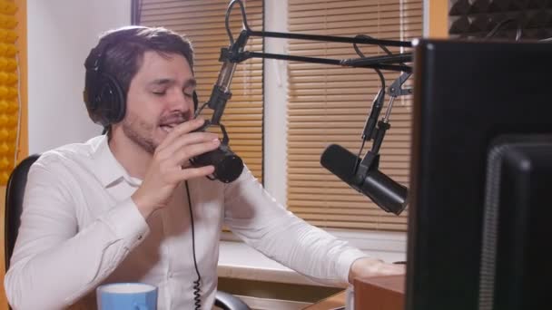 Kulaklık mikrofon üzerinde konuşmaya olan genç adam. Online radyo ve podcasting kavramı. — Stok video