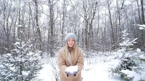 El concepto de Navidad y vacaciones de invierno. Mujer feliz lanza nieve en el bosque de invierno — Vídeo de stock