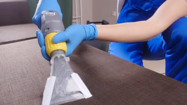 Concept of cleaning in the apartment and office. Dry cleaning worker removing dirt from sofa indoors — Stock Video