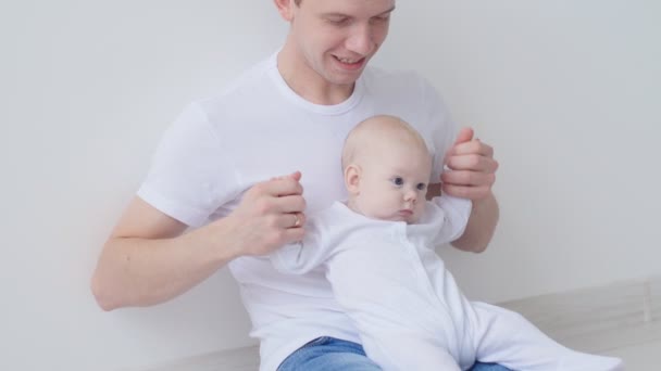 Joven padre feliz pasa tiempo con su bebé en el interior blanco — Vídeos de Stock