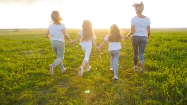 Концепция дружбы. Молодые счастливые женщины с дочерьми бегут по полю на закате — стоковое видео