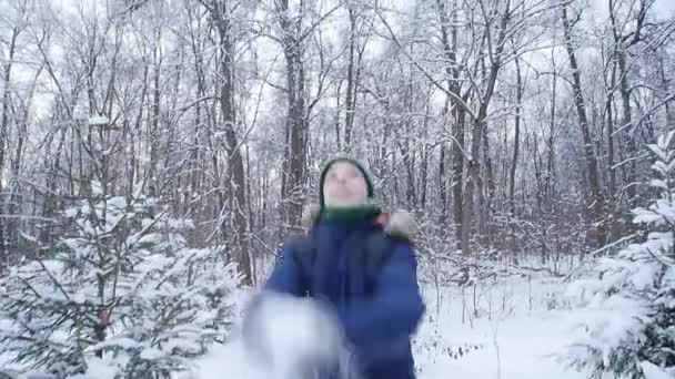 Niño adolescente lanza nieve en el bosque de invierno. Estilo de vida activo, actividad invernal, concepto de juegos de invierno al aire libre — Vídeo de stock