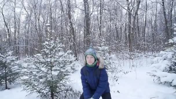 快乐的青少年男孩扔雪在冬天的森林 积极的生活方式 冬季活动 户外冬季运动的概念 — 图库视频影像