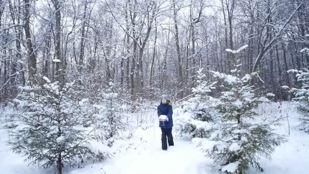 Tonårspojken kastar snö i vinterskogen. Aktiv livsstil, vinteraktivitet, utomhus vinterspel koncept — Stockvideo