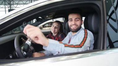 Satın alma veya bir araba kiralamak kavramı. Yeni araba anahtarları ile genç mutlu ırklararası çift