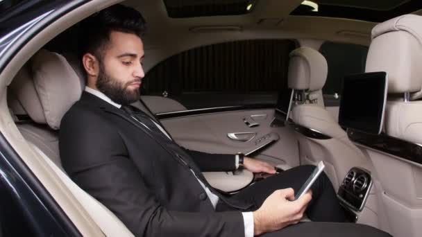 Молодой бизнесмен разговаривает по телефону в машине — стоковое видео