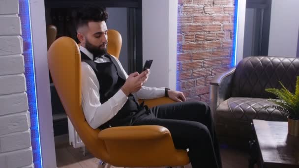 Fiatal férfi ült a székében okostelefon — Stock videók