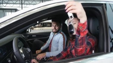 Mutlu genç bir çift yeni bir araba satın alıyor. Gülümsüyor ve ihtiyacınız olan tușları gösteren