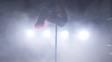 Dans ve akrobasi kavramı. Seksi kadın kutup ışıkları ve duman ile karanlık iç dans