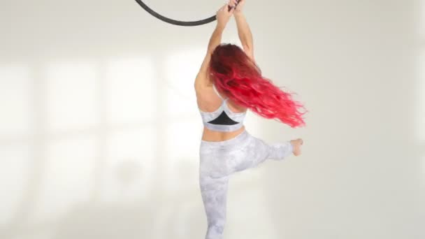 Концепція танцю та акробатики. Молода жінка в повітряному кільці на білому тлі — стокове відео