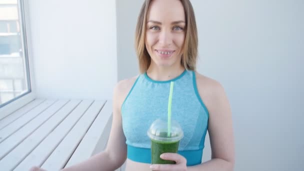 Concepto de deporte y estilo de vida saludable: mujer joven bebiendo batido verde — Vídeos de Stock
